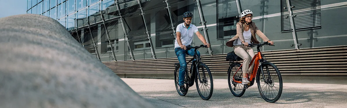 Zwei Personen fahren KTM Macina Sport SX E-Bikes im Stadtalltag