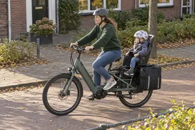Mutter und Kind mit Helmen auf einem elektrischen Longtail-Lastenrad