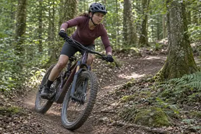 Fahrerin mit einem vollgefederten E-Mountainbike auf einem Waldtrail