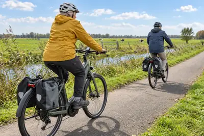 Paar auf Trekking-E-Bikes bei einer sonnigen Tour durch die Landschaft